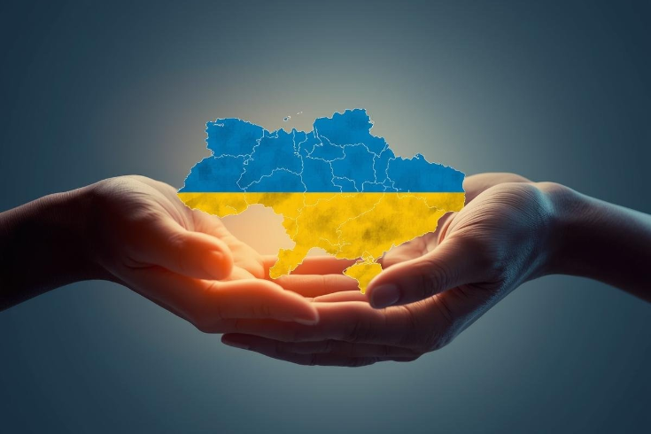 dwie dłonie trzymają mapę Ukrainy w barwach flagi